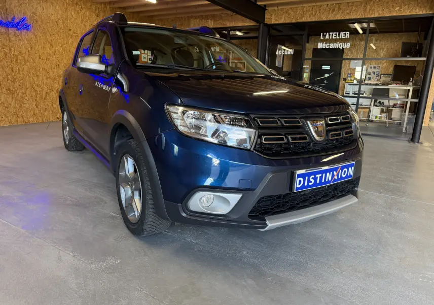 Vue 3/4 avant gauche d'une Dacia Sandero Stepway bleu foncé 2019 avec calandre noire et protections plastiques noires.