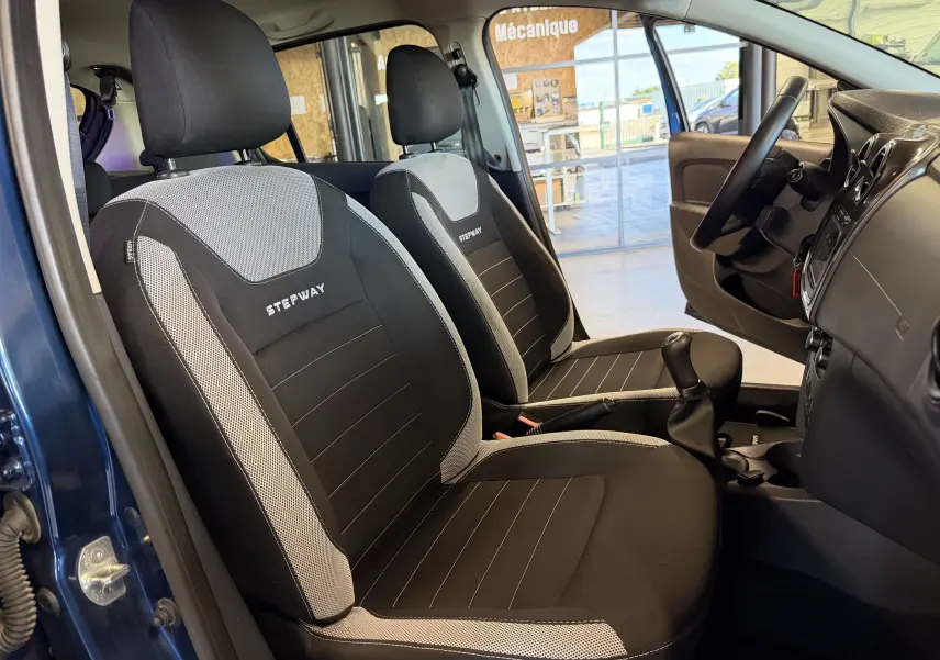 Vue intérieure côté conducteur du Dacia Sandero Stepway bleu 2019, sièges noirs avec logo Stepway brodé.