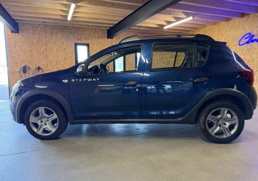 Vue de profil côté gauche d'une Dacia Sandero Stepway bleue avec logo Stepway visible sur la porte avant.