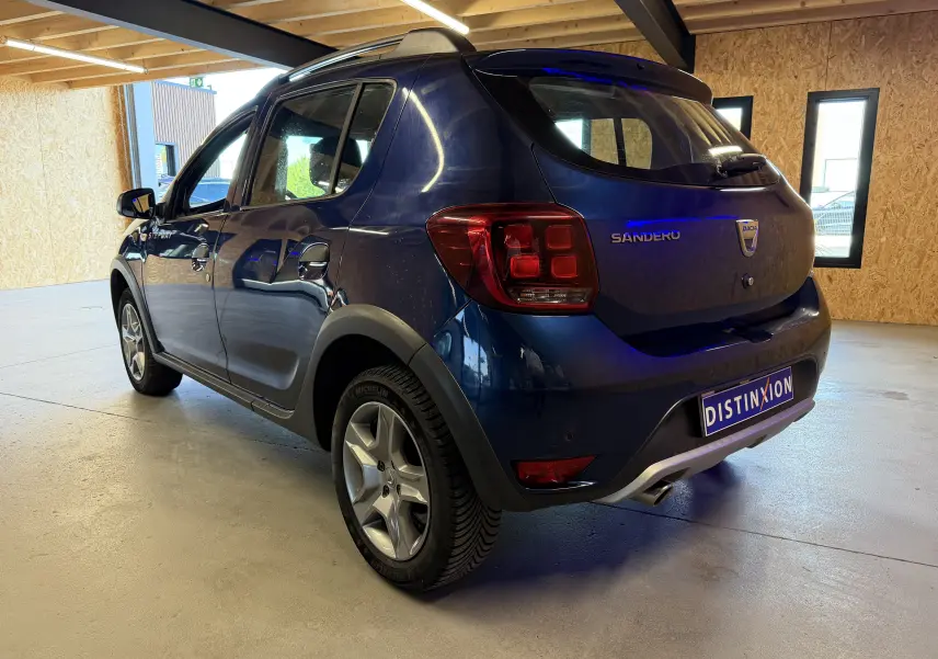Vue 3/4 arrière droite d'une Dacia Sandero Stepway bleu foncé 2019 avec jantes alliage et protections noires.