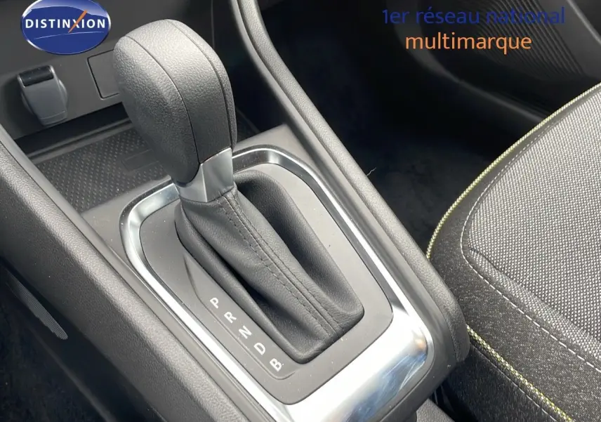 Le levier de vitesses automatique en cuir noir de la Renault Captur E-Tech Hybrid 2025, avec partie centrale et siège tissu gris.