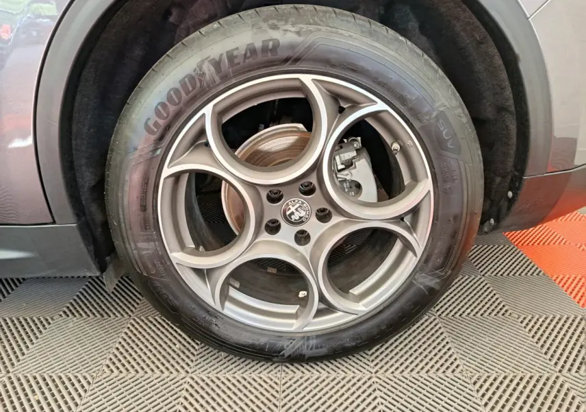 Gros plan sur la roue avant droite gris foncé d’un Alfa Romeo Stelvio 2024 avec jante en alliage à motif circulaire distinctif.