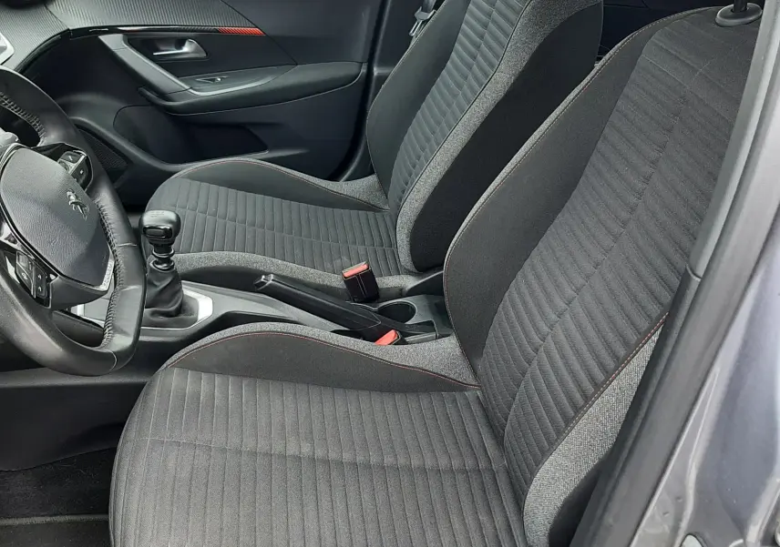 Vue intérieure côté conducteur du Peugeot 2008 1.5 BlueHDi 2020, sièges tissu gris foncé avec surpiqûres orange.