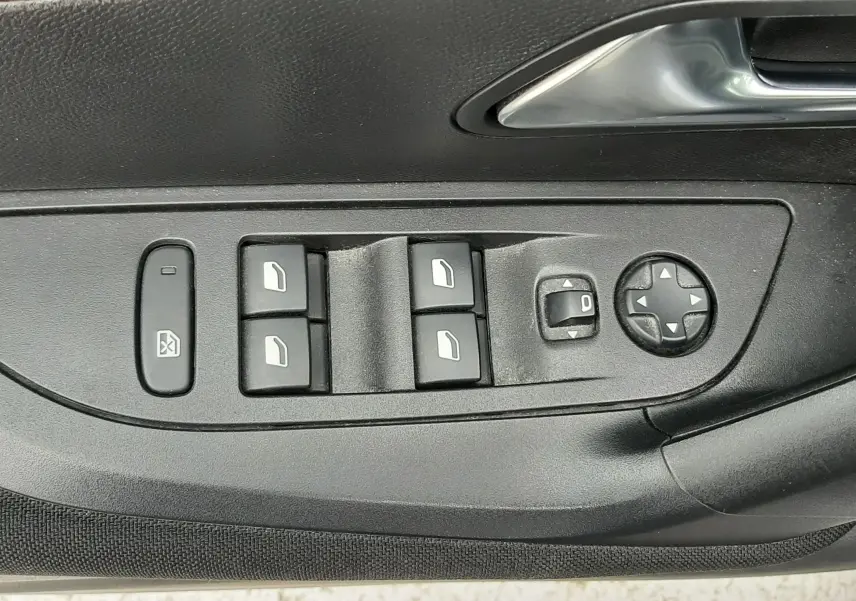Gros plan sur la commande des vitres et rétroviseurs électriques côté conducteur d'une Peugeot 2008 gris Artense.