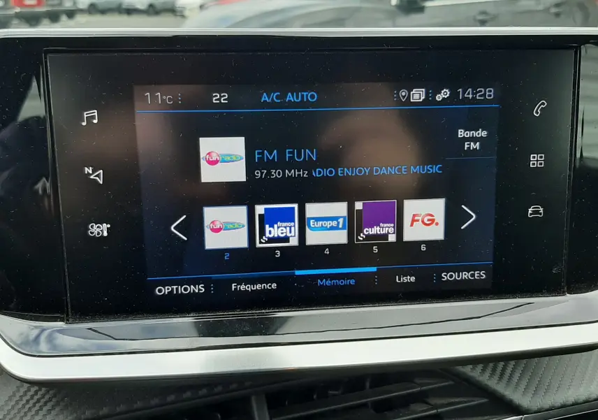 Vue intérieure centrée sur l'écran tactile multimédia du Peugeot 2008, affichant les radios FM avec commandes tactiles.