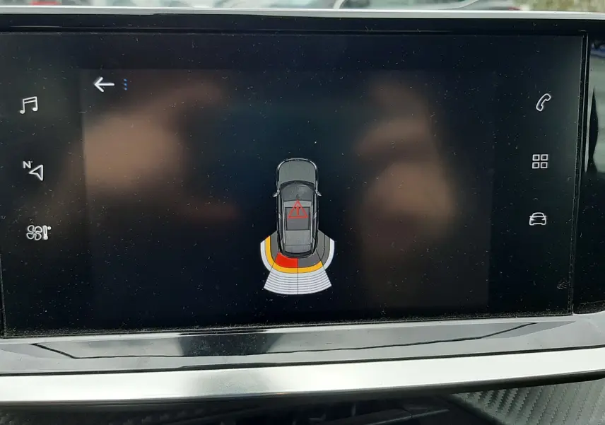 Écran tactile intérieur affichant le système d’aide au stationnement du Peugeot 2008 gris Artense, vue de face du tableau de bord.