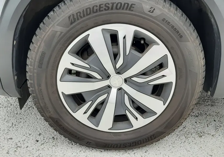 Gros plan sur la roue avant droite d’un Peugeot 2008 gris Artense avec jante alliage au design moderne et pneu Bridgestone.