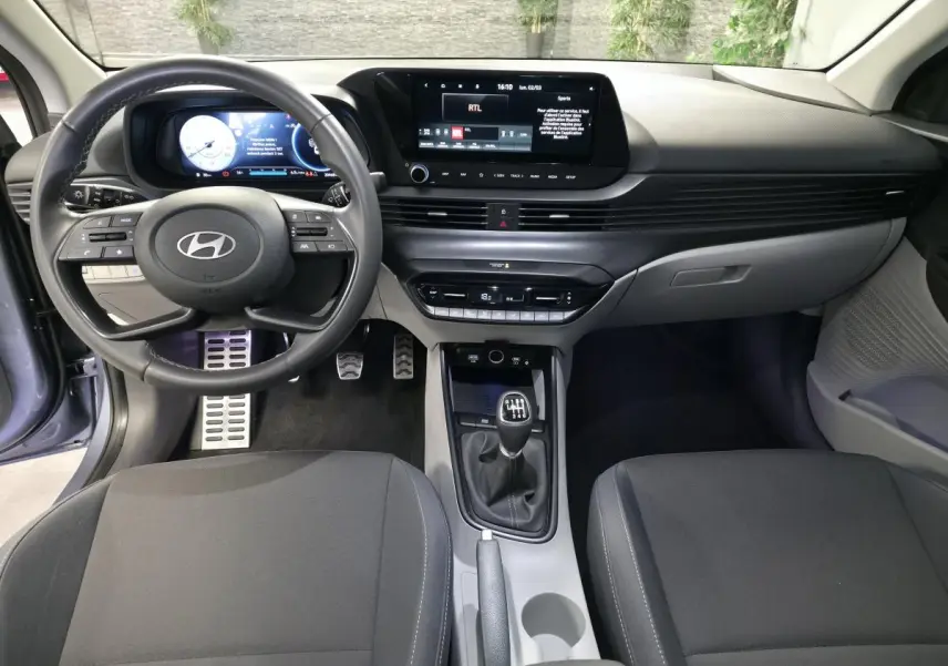 Vue intérieure avant du Hyundai Bayon 2025 essence gris, volant cuir, écran tactile 10,25 pouces et boîte manuelle.