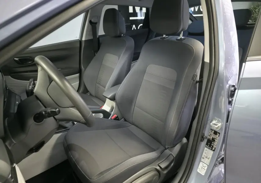 Vue intérieure côté conducteur du Hyundai Bayon gris 2025, mettant en valeur les sièges avant bi-ton noir et gris clair.