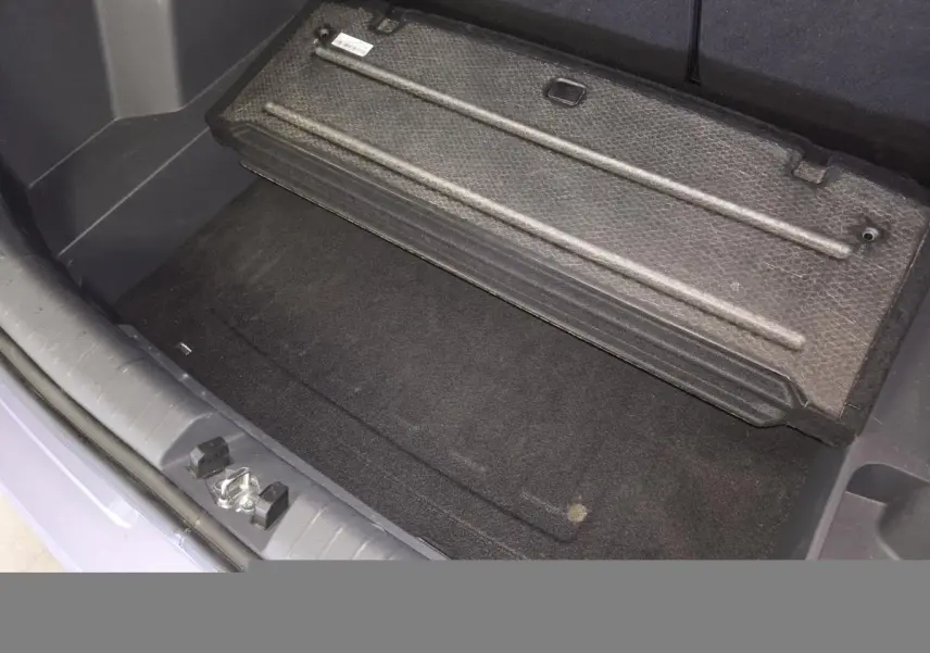 Vue rapprochée du coffre ouvert de la Hyundai Bayon gris, montrant le plancher modulable et la trappe de rangement.