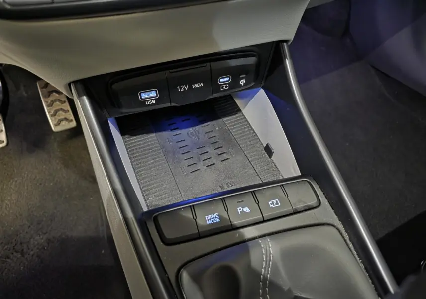 Gros plan sur la console centrale grise du Hyundai Bayon 2025 avec chargeur sans fil et ports USB éclairés.