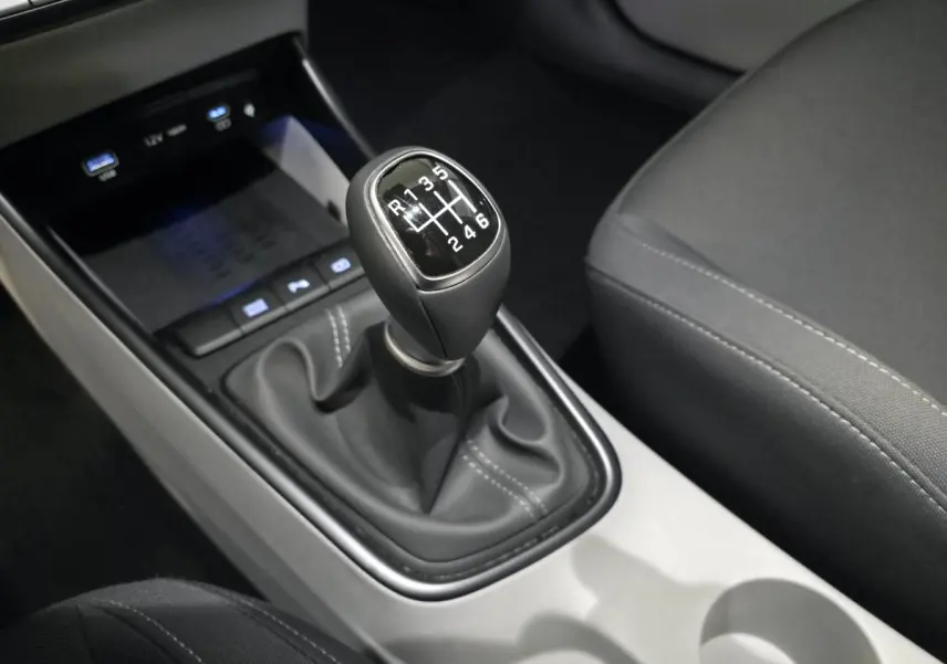 Gros plan sur le levier de vitesses manuel noir et gris clair du Hyundai Bayon 2025, intérieur tissu sombre.