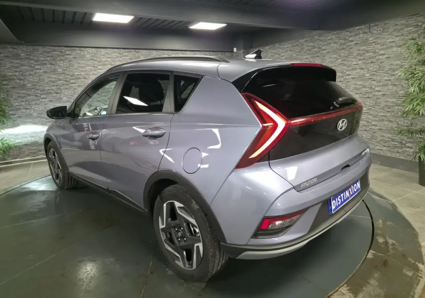 Vue 3/4 arrière droite du Hyundai Bayon gris métallisé avec feux arrière LED en forme de flèche et jantes alliage 17 pouces.