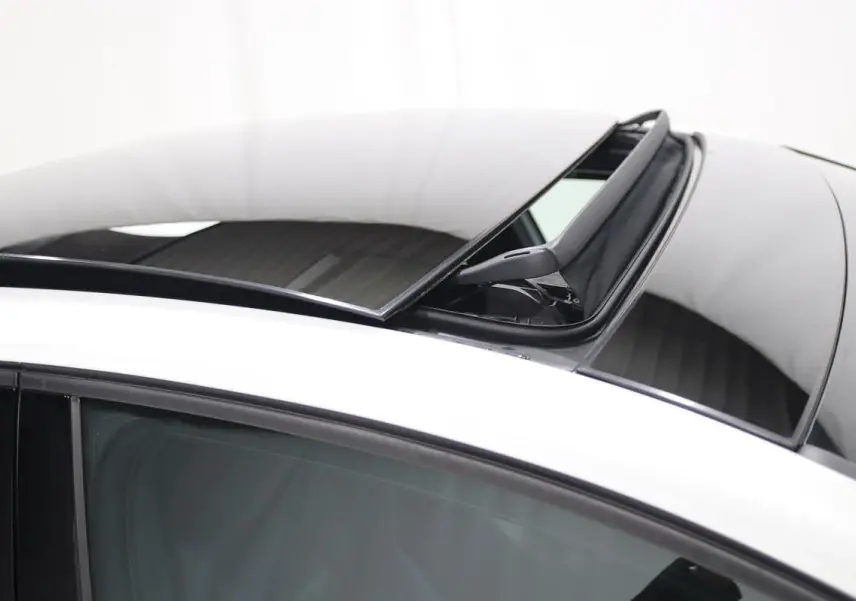 Toit panoramique ouvert sur une Volkswagen Golf blanche, vue rapprochée du toit et vitre côté gauche.