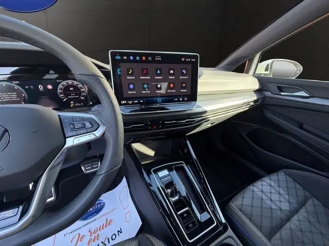 Vue intérieure avant droite de la Volkswagen Golf 2.0 TDI 150 DSG R-Line 2025 avec écran tactile, volant cuir multifonctions et sellerie sport.
