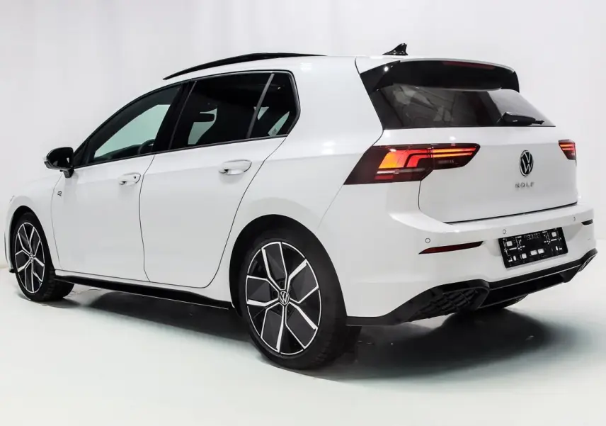 Vue 3/4 arrière droite d'une Volkswagen Golf blanche 2025 avec jantes alliage et toit panoramique noir.