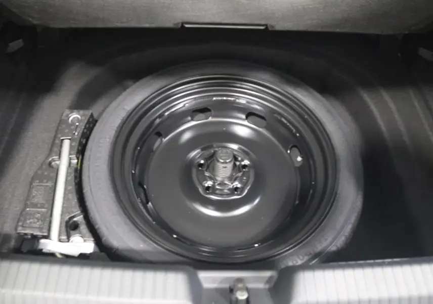 Gros plan sur la roue de secours noire dans le coffre d'une Volkswagen Golf blanche 2025.