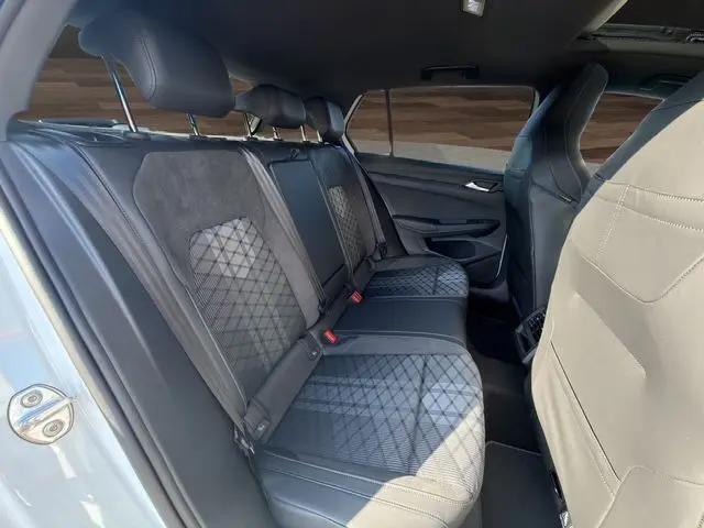 Vue intérieure arrière droite de la Volkswagen Golf 2.0 TDI R-Line 2025 avec sièges sport en cuir et toit panoramique visible.