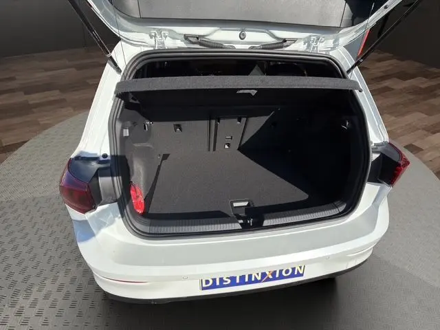 Vue arrière ouverte d'une Volkswagen Golf blanche 2025, coffre spacieux et tapis noir visible, feux arrière LED.