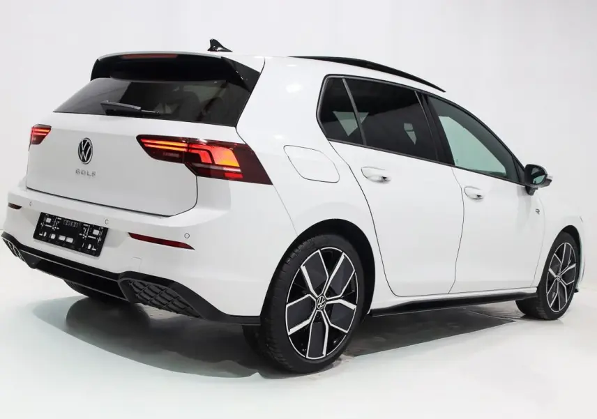 Vue 3/4 arrière droite d'une Volkswagen Golf blanche 2025 avec jantes alliage noires et toit panoramique noir.