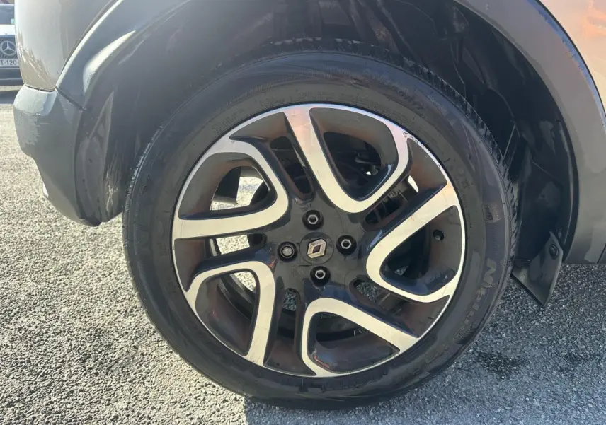 Gros plan sur la jante alliage 17 pouces noir diamanté du Renault Captur beige, avec logo Renault central.