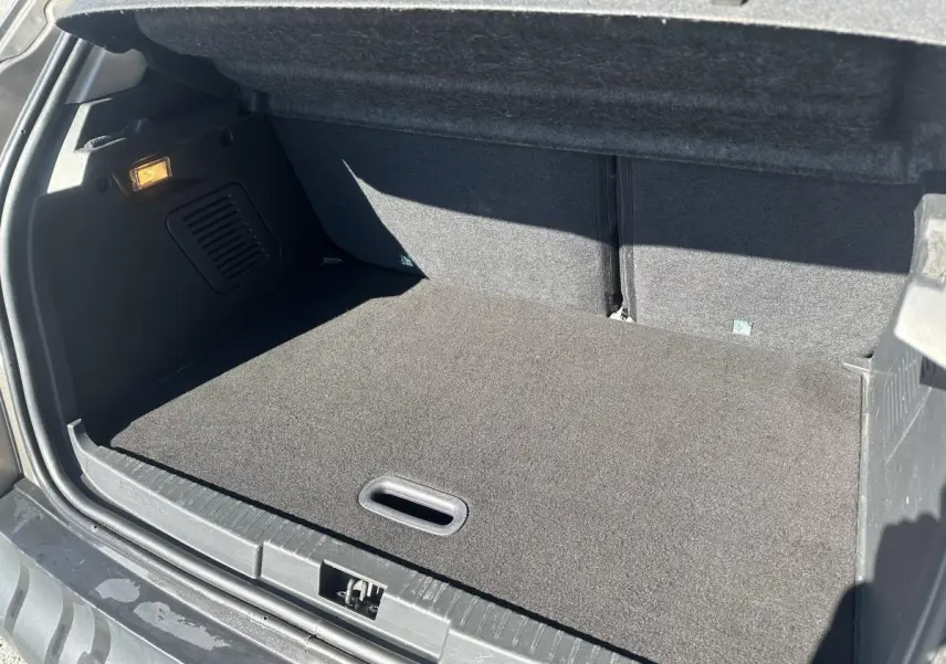 Coffre ouvert du Renault Captur beige 2014, vue arrière montrant un espace de chargement propre et tapis gris.