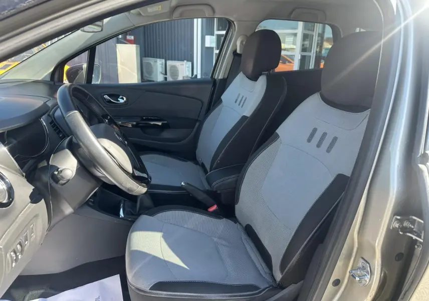Vue intérieure côté conducteur du Renault Captur beige 2014, mettant en valeur les sièges déhoussables gris et noirs.