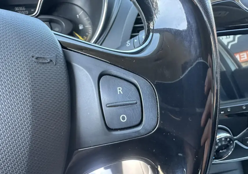 Gros plan sur le volant noir du Renault Captur 2014, avec boutons de commande et tableau de bord partiellement visible.