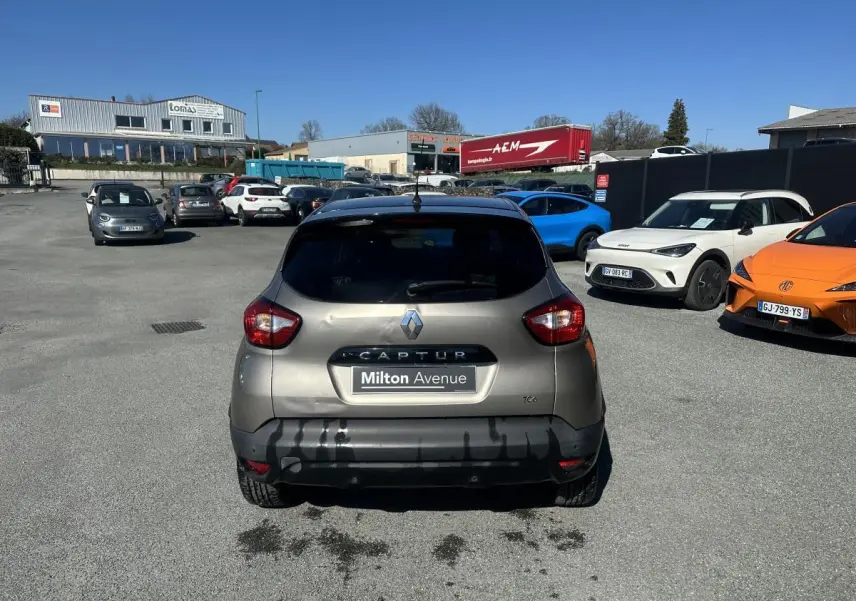 Vue arrière d'un Renault Captur beige métallisé 2014 avec toit noir, stationné sur un parking ensoleillé.