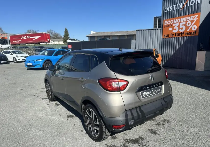 Vue 3/4 arrière droite d’un Renault Captur beige métallisé avec toit noir et jantes alliage noires diamantées.