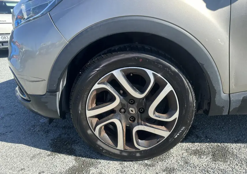 Gros plan sur la roue avant gauche alliage noir diamanté du Renault Captur beige 2014 avec jante stylisée.