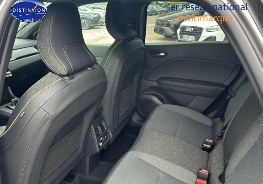 Vue intérieure arrière côté droit du Renault Captur gris cassiopée, montrant les sièges arrière et les dossiers avant en tissu et cuir.