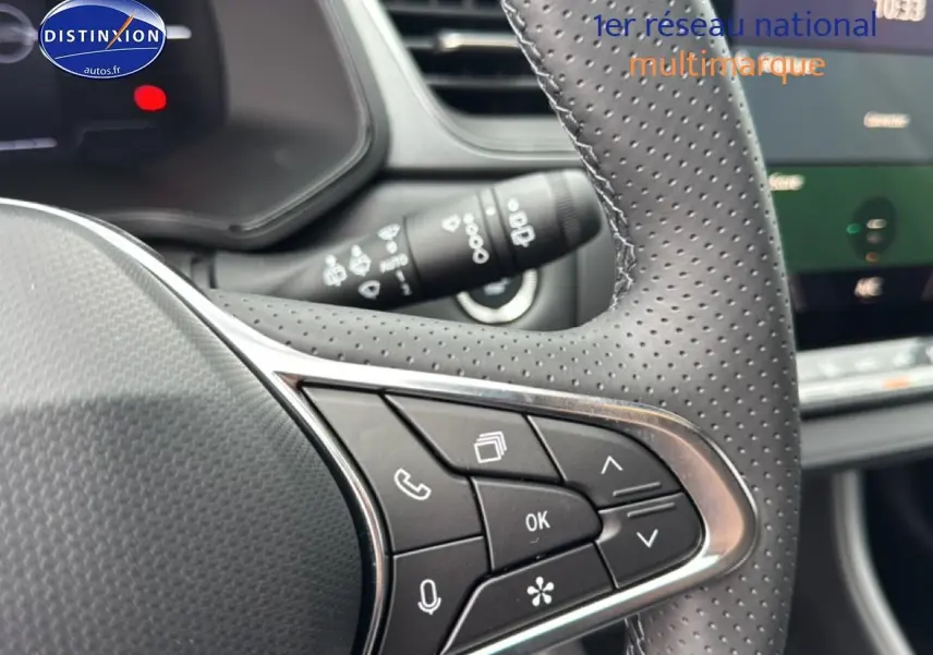 Gros plan sur les commandes au volant côté droit du Renault Captur gris cassiopée, avec tableau de bord en arrière-plan flou.