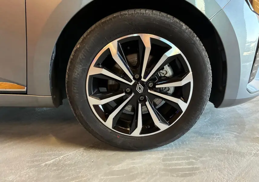 Gros plan sur la roue avant droite de la Renault Clio gris schiste, mettant en valeur la jante alliage bicolore au design moderne.