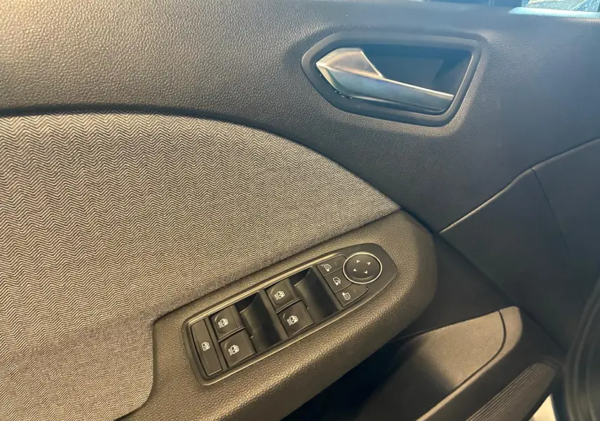 Détail de la porte intérieure côté conducteur de la Renault Clio 2025 gris schiste, avec commandes des vitres et poignée argentée.