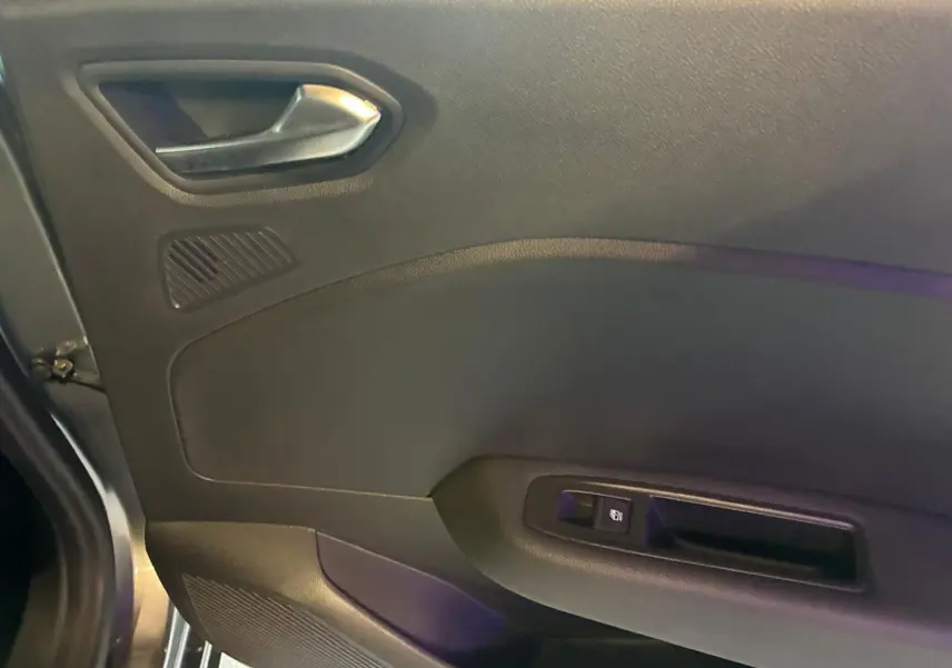 Détail de la porte intérieure côté gauche de la Renault Clio gris schiste, avec poignée argentée et commande de fenêtre.