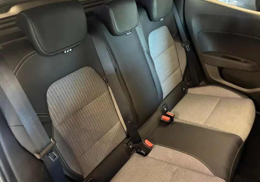 Vue intérieure sur les sièges arrière gris clair et noir de la Renault Clio hybride 2025, avec ceintures de sécurité visibles.