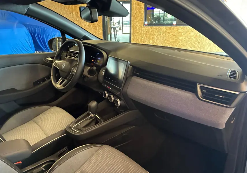 Vue intérieure côté conducteur de la Renault Clio 2025 gris schiste, avec tableau de bord moderne et écran tactile central.