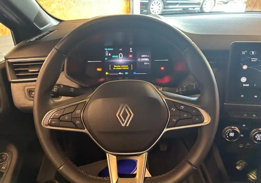 Vue intérieure centrée sur le volant noir de la Renault Clio 2025 avec tableau de bord numérique et écran tactile.