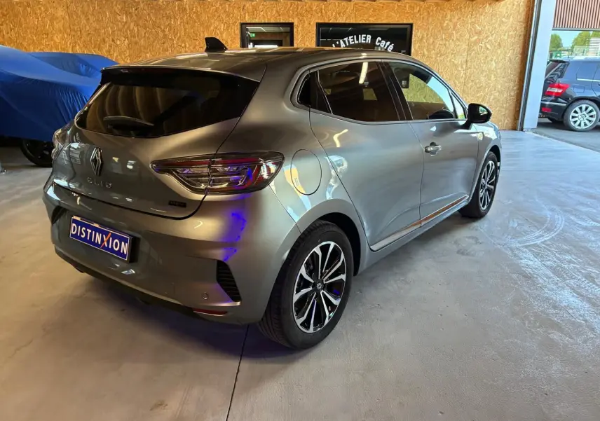 Vue 3/4 arrière droite d'une Renault Clio gris schiste 2025 avec feux LED et jantes alliage noires et argentées.
