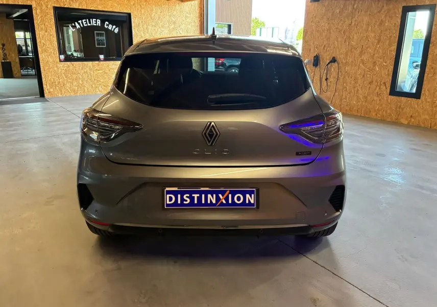 Vue arrière d'une Renault Clio gris schiste hybride 2025, avec feux LED et logo distinctif visible en intérieur.