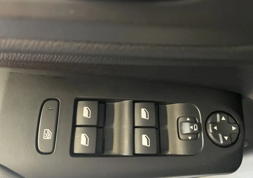 Gros plan sur les commandes de lève-vitres et réglages des rétroviseurs côté conducteur d’un Citroën C5 Aircross blanc 2025.