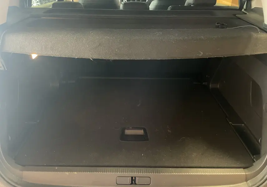 Coffre ouvert vu de l'arrière d'un Citroën C5 Aircross hybride blanc Okenite, espace de chargement vide avec cache-bagages.
