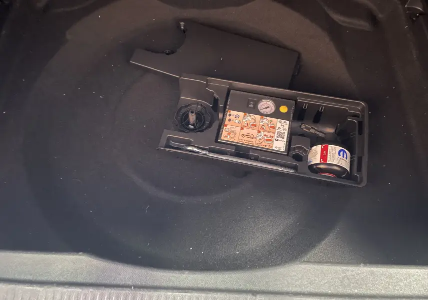 Vue rapprochée du coffre d'un Citroën C5 Aircross blanc Okenite 2025, montrant le kit de réparation pneu intégré.