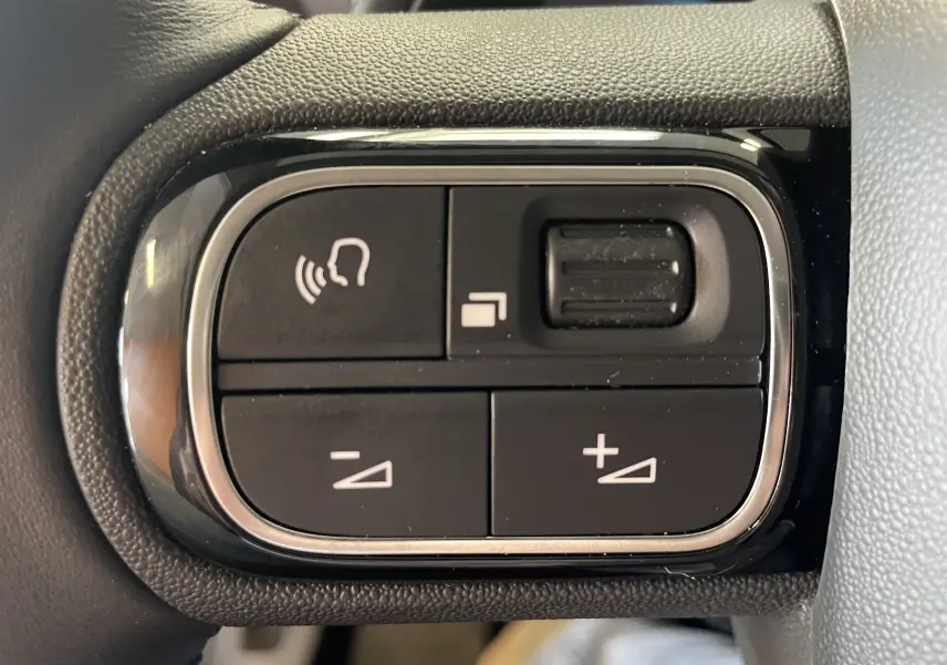 Gros plan sur les boutons de commande au volant du Citroën C5 Aircross blanc Okenite, version hybride 2025.