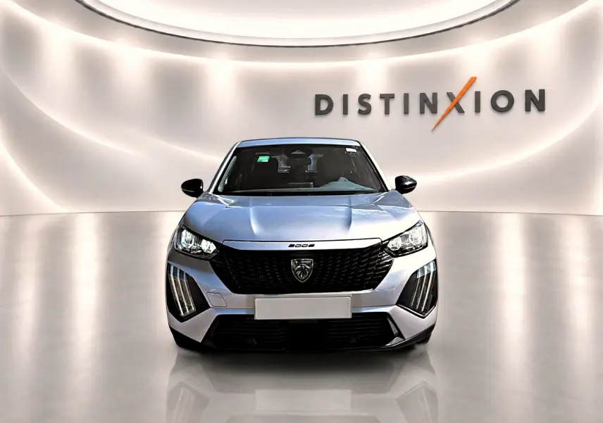 Vue frontale d'un Peugeot 2008 gris 2025 avec calandre noire et feux LED distinctifs dans un showroom lumineux.