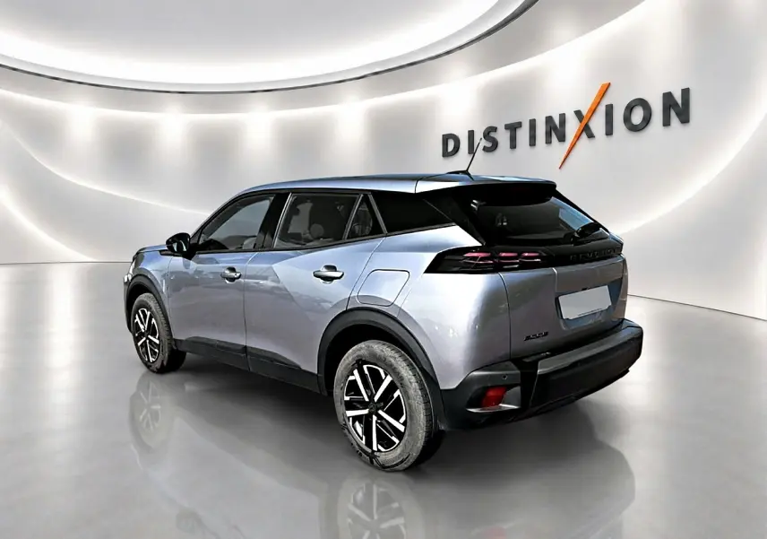 Peugeot 2008 gris 3/4 arrière droit en intérieur avec toit noir et jantes bicolores distinctives.