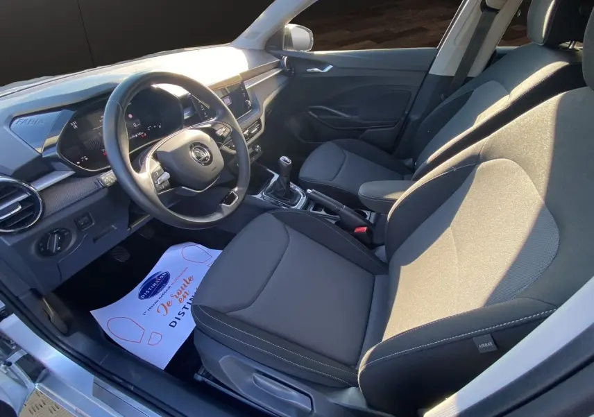 Intérieur avant droit de la Skoda Fabia 2024 avec sellerie tissu noire et console centrale avec boîte manuelle.