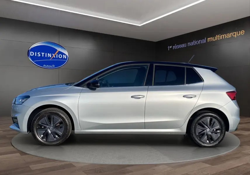 Profil droit d'une Skoda Fabia 2024 gris clair avec toit noir et jantes modernes en concession.