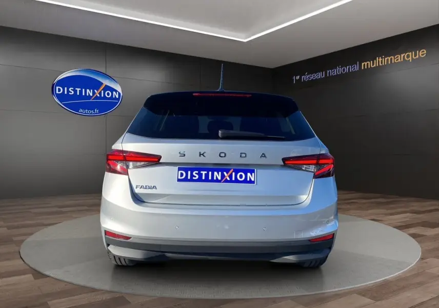 Vue arrière d'une Skoda Fabia 2024 gris clair avec toit noir, feux LED et logo distinctif sur fond showroom.